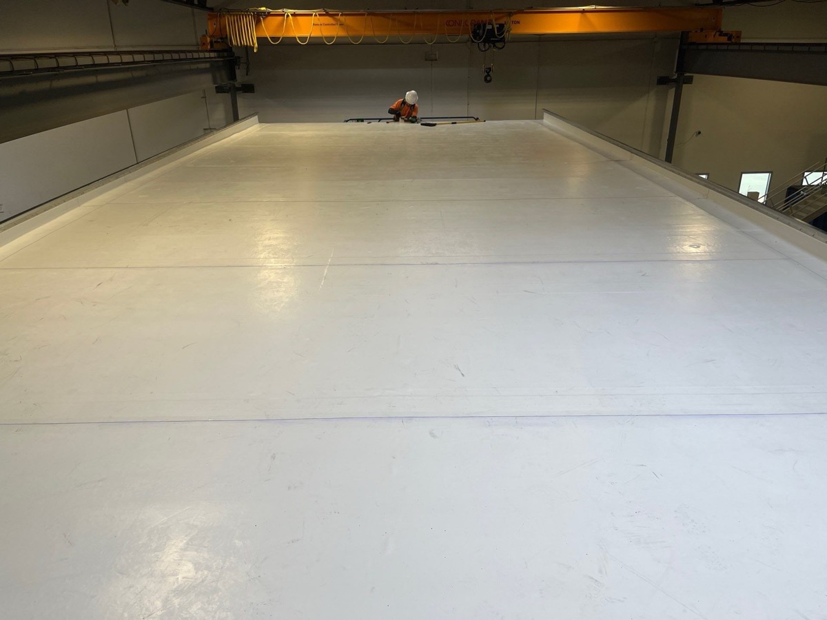 Crew member completing installation of white membrane roof section